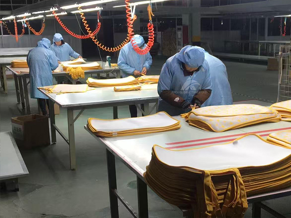 Workers sewing finished blankets in home textile workshop, post‑production assembly process