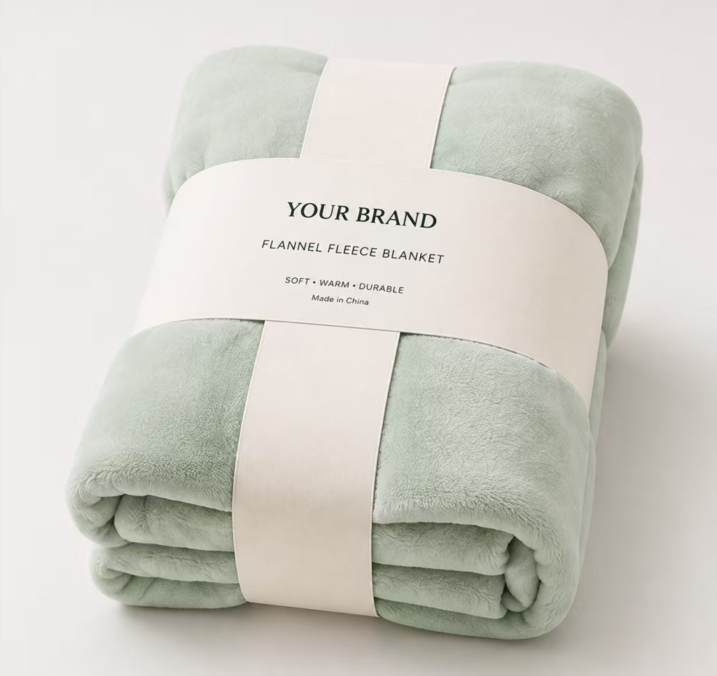 Custom‑branded light‑green flannel fleece blanket with paper band, neatly folded for retail display