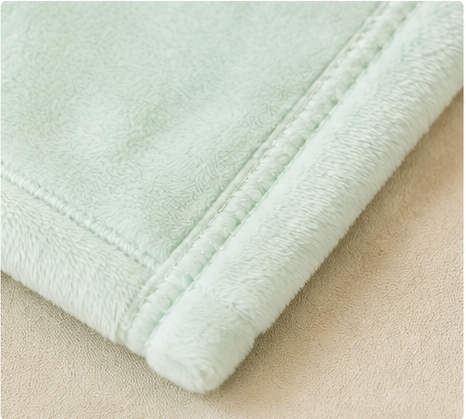 Soft plush light‑green flannel blanket, close‑up of fine edge stitching detail