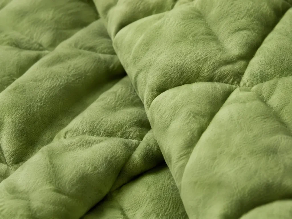 Close‑up view of soft green quilted home textile fabric