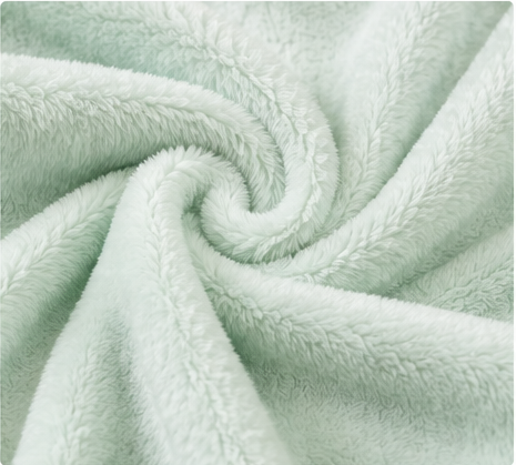 Cozy fuzzy light‑green flannel blanket, close‑up of soft fabric texture